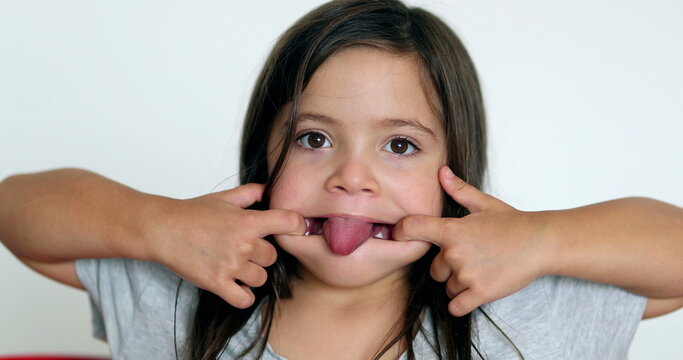 Little girl grimacing, sticking ongue out. Child grimace making funny faces - Powered by Adobe