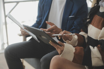 Young woman and young man using laptop while sitting by the sofa at home