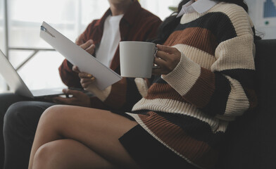 Young woman and young man using laptop while sitting by the sofa at home