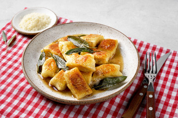 Italian homemade gnocchi with potatoes, cheese and sage butter, served in plate on red napkin