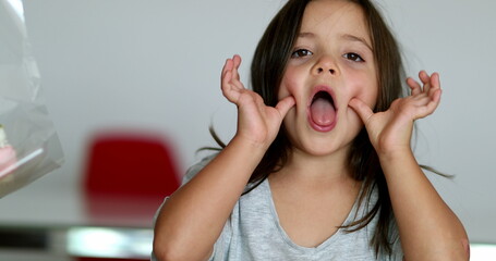 Little girl grimacing to camera sticking tongue out. Child teasing