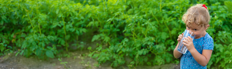 A child drinks water from a glass. Selective focus.