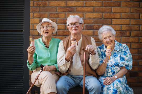 Three senior friends in the city, eating ice cream on a hot summer day. Summer vacation in the city. Pensioners on group trip. Concept of senior vacation and travel groups, clubs.