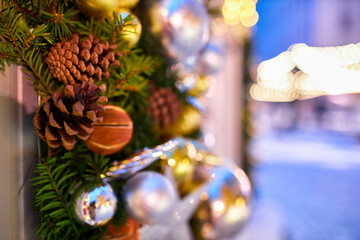 The lights of the garland decorate the house and the Christmas tree, on the branch there is a red sparkling ball. Christmas tree in the evening city on New Year's Eve.