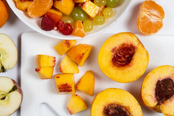 Cooking a fruit salad from an assortment of fruits and berries - cutting the nectarine into pieces