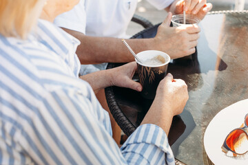An elderly couple, a man and a woman, are drinking frappuccino and cappuccino.
