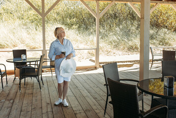 Portrait of an elderly woman standing in a cafe with a mug and drinking coffee