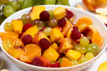Fruit salad with sliced fruit, mixed grapes, raspberries, nectarines, tangerines and apples