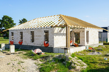 Fototapeta na wymiar Unfinished residential house with white concrete block walls and a wooden beam truss roof structure
