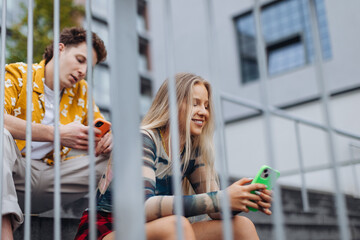 Couple sitting on concrete steps, each scrolling on their smartphone. Together in person, but alone...