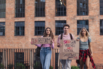 Generation Z activists with banners protesting on the street. Young students marching through the...