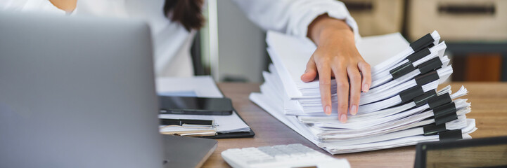 auditor with stack of paperwork with unfinished documents achieves.