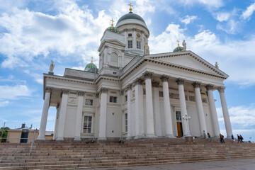 Fototapeta na wymiar Helsinki Cathedral with people walking, sunny day with some clouds.