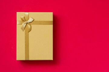 Golden (yellow) box, gift on redbackground. Greeting concept for Birthday, Christmas, Valentine's Day, Mother's Day.
