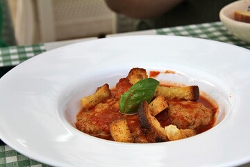 plate with meatballs, tomato sauce, pieces of dry sliced bread, fresh basil, Italian cuisine