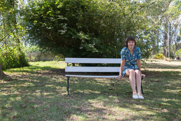 Mujer bella sentada en el banco de un parque