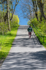 Woman jogging up a steep hill in spring.
