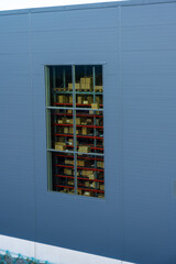Boxes and pallets visible through a window at a large warehouse.