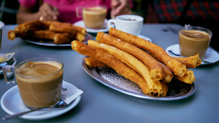 Churros popular deliciuos spanish food with hot chocolate and coffe on restaurant table