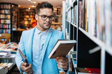 Middle age man choosing and reading books in modern bookstore.