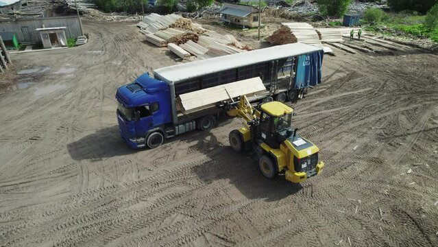Aerial view of finished lumber being loaded into a semi-trailer for transportation to a customer from a timber processing facility.