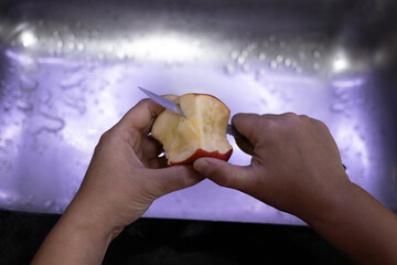 hands cutting a piece of apple with knife