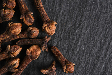 Spices clove seeds slate stone background.