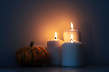 Orange Halloween pumpkins and candles on wooden table, holiday decoration, evening time. Preparation for Halloween celebrating.
