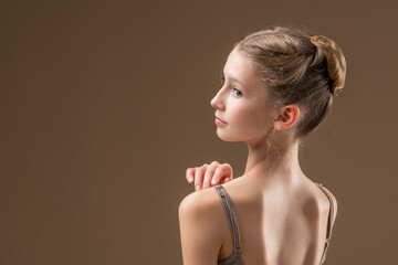 Portrait of a beautiful young girl professional ballerina student with pointe shoes in a leotard on a light beige background. © Maria Moroz