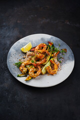 Traditional Thai fried king prawns with Asian vegetable and rice served as close-up on a design plate with text space