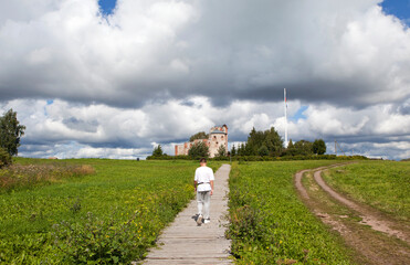 Obraz premium A teenager walks along the flooring to the Church of the Annunciation of the Blessed Virgin Mary. Rurik's Settlement. Velikiy Novgorod. Russia