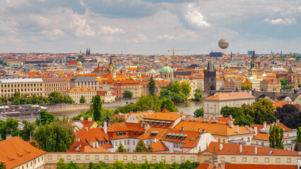 Fototapeta na wymiar Prague, Czech Republic. Panoramic over Vltava river with big tour boats, famous Charles Bridge, touristic air balloon, tourists at walking embankment in historical downtown of city