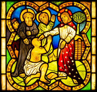 Stained glass church window with scenes of mercy and the lives of saints	
