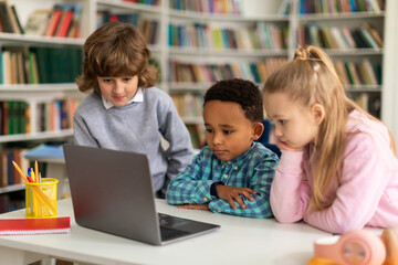 Fototapeta na wymiar Diverse kids watching educational videos on laptop computer in classroom