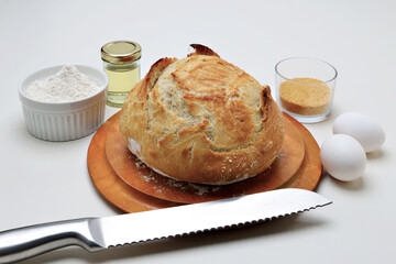 Pão artesanal em fundo branco com faca de corte e ingredientes