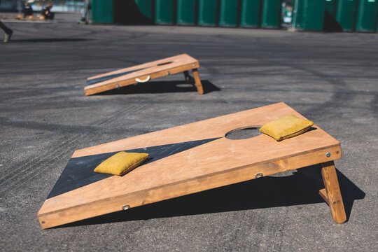 Cornhole Game Set, Process Of Throwing Bean Bags, Kids Children Tossing Bean Sacks, Corn Hole  In The Backyard, Wooden Boards For Corn-hole Tournament In The Summer Sunny Day