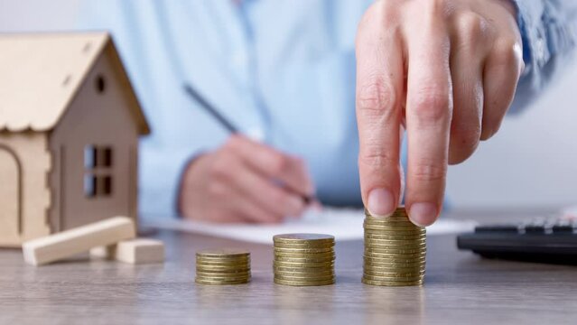 Saving money to buy a house. Coins in a woman's hand as an investment in real estate. Mortgage concept.