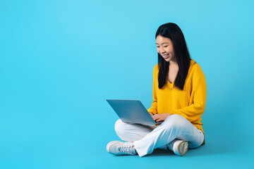 positive young asian woman independent contractor working on laptop
