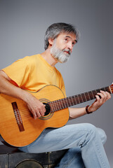 Obraz premium Aged bearded man with an acoustic guitar