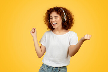 European teen woman enjoys music via headphones, yellow