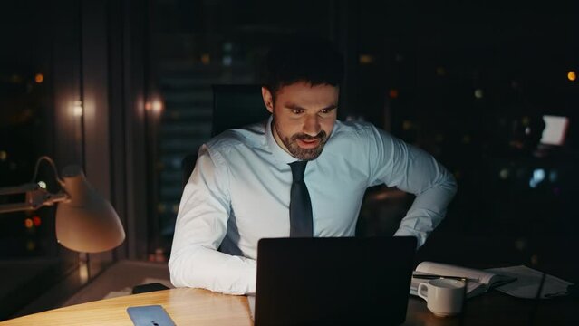 Successful businessman working late evening in modern office alone close up.
