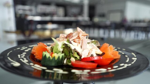 video 360 rotation of a plate with vegetable salad,cold cuts,jamon, decorated with chopped vegetables with a decorative pattern of spices and sauce. presentation of food on a rotating platform