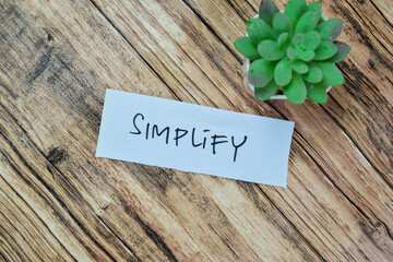 Concept of Simplify write on sticky notes isolated on Wooden Table.