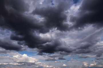 Storm dark grey cumulus rain clouds against blue sky background texture, thunderstorm