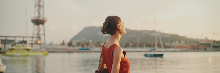 Girl stands on the embankment and looks at the bay. Young woman looks at the sea in the morning...