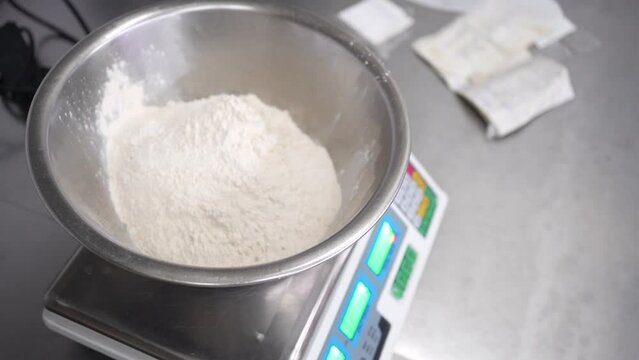 Baker weighing flour in a bowl on electonic balance