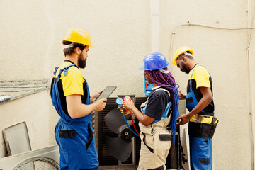 Competent mechanics diverse team hired by client to search for refrigerant leaks on outdoor air...