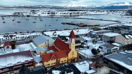 Snowfall Town At Ushuaia In Tierra Del Fuego Argentina. Snowy Landscape. Outdoor Aerial View. Tierra Del Fuego Argentina. Frozen Cityscape. Snowfall Town At Ushuaia In Tierra Del Fuego Argentina. - obrazy, fototapety, plakaty