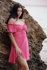 Beautiful woman in pink dress posing near cliff