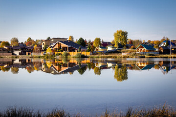Fototapeta premium Houses in the countryside by the lake on a clear sunny day in autumn